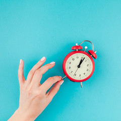 Woman hand holding the red vintage alarm clock