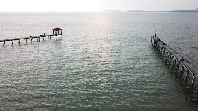 Aerial view of beautiful beach, old jetty with unidentified people, logo or brand during sunset. 