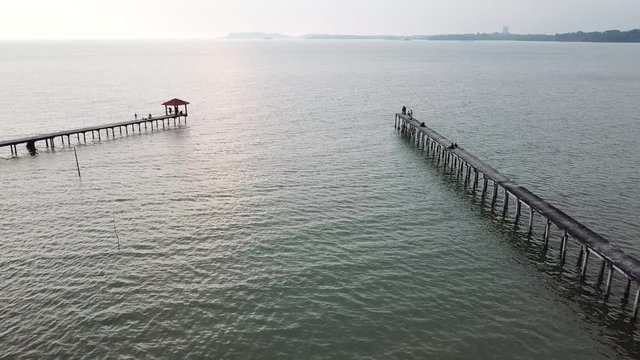 Aerial view of beautiful beach, old jetty with unidentified people, logo or brand during sunset. 