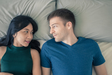 Couple with good communication skills.  White background laying on bed and happy.