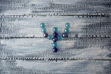 The letter of the Greek alphabet is psi. Multicolored glass balls on a wooden background. Modern...