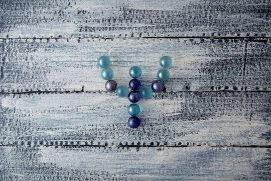 The letter of the Greek alphabet is psi. Multicolored glass balls on a wooden background. Modern logo of Psychology. Psi. Glass marbles. - Powered by Adobe