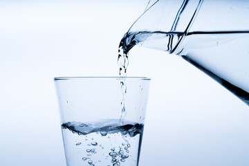 Glass of water with pouring from the bottle, studio shot