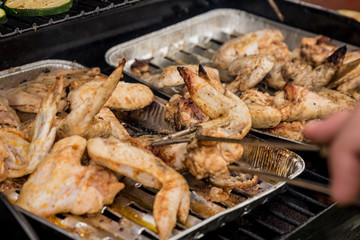 Marinated chicken wings on grilled hand chefs turning meat