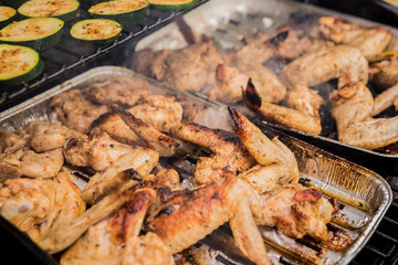 Marinated chicken wings on grilled hand chefs turning meat