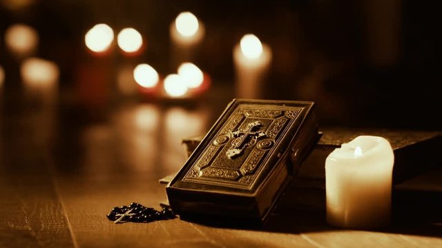 Antique Holy Bible and burning candles in the Church
