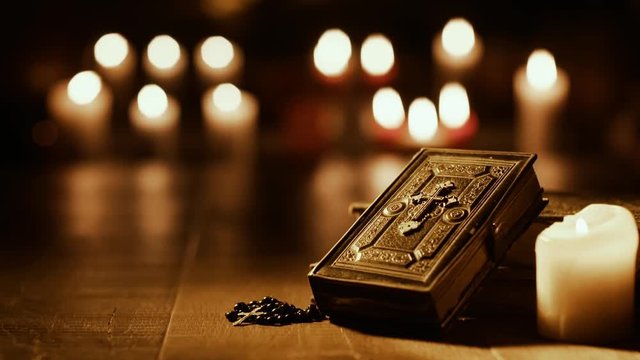 Antique Holy Bible and burning candles in the Church