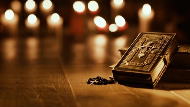 Antique Holy Bible and burning candles in the Church