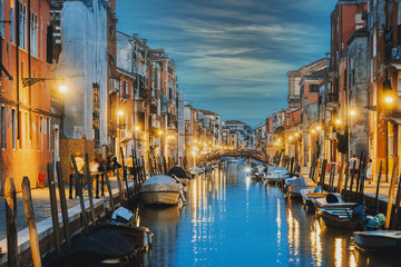 Water canal and colorful historic houses at night in Venice, Italy