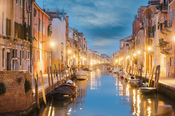 Water canal and colorful historic houses at night in Venice, Italy