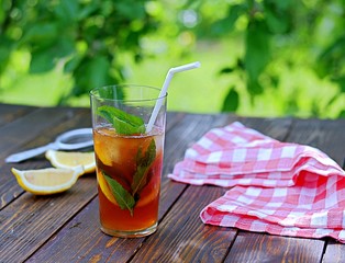 Cool drink, cold black tea with lemon, mint and ice in tall glasses. Summer concept