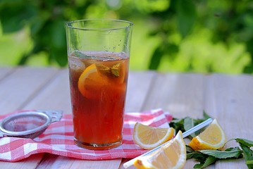 Cool drink, cold black tea with lemon, mint and ice in tall glasses. Summer concept