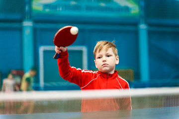 boy playing table tennis indoors