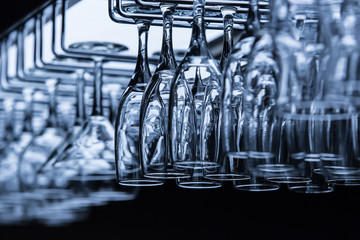 Clean wineglasses and goblets hang on bar counter.