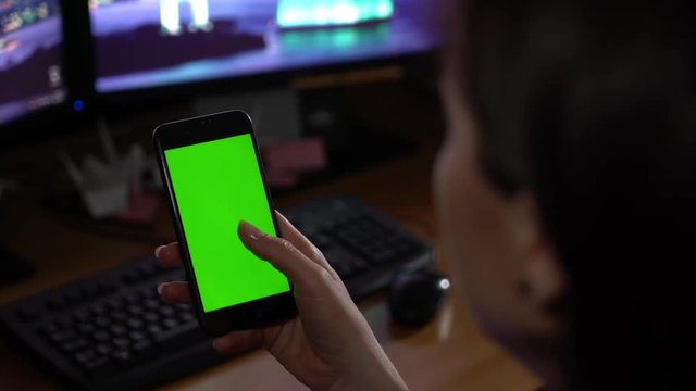 A woman is holding a phone with a green screen.