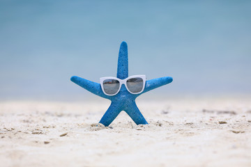 Fototapeta na wymiar blue starfish and sunglasses on the beach sand