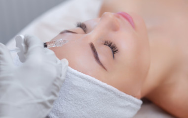 Fototapeta na wymiar The doctor cosmetologist makes the Rejuvenating facial injections procedure for tightening and smoothing wrinkles on the face skin of a beautiful, young woman in a beauty salon.Cosmetology skin care.