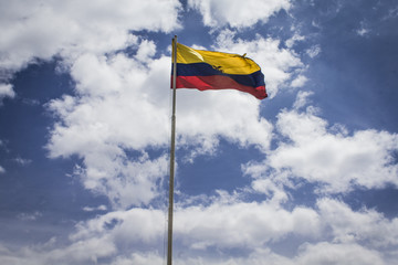 Flag of the Republic of Ecuador, on a sunny day with the city of Quito in the background.