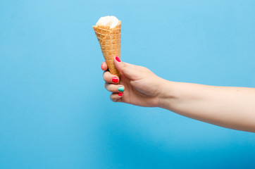Tasty ice cream in a female hand on a blue background