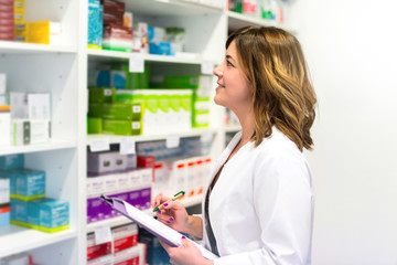 Woman customer with a folder in the pharmacy looking at the medicines on the shelf
