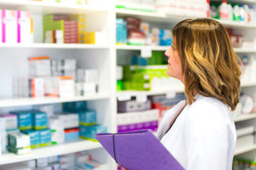 Woman customer with a folder in the pharmacy looking at the medicines on the shelf