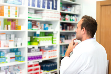 Adult man pharmacist in pharmacy looking for medications
