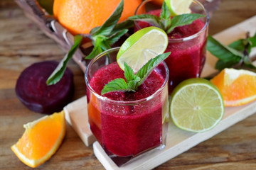 Smoothie with beet and orange in a glass decorated with mint and a slice of lime