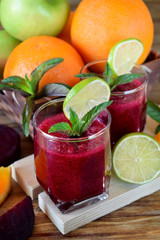 Smoothie with beet and orange in a glass decorated with mint and a slice of lime