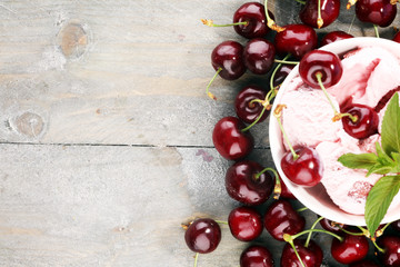 Homemade cherry ice cream and a bunch of cherries on table