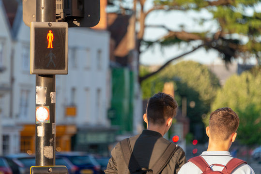 stop and search security policy with red stop sign and two young men with backpacks walking down street