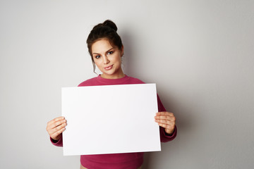 Pretty young woman holding empty blank board isolated on the gray background