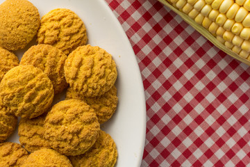 Delicious yellow cookie of corn. Sweet food of Festa Junina, a typical brazilian party. Snack on plate, red plaid table.