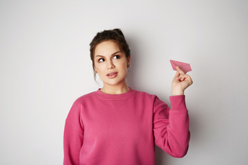 Travel air plane concept.Young pretty woman holding hand model pink paper air plane. Design of travel concept with plane on empty gray color background