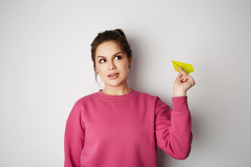 Travel air plane concept.Young pretty woman holding hand model yellow paper air plane. Emotions, people, beauty, fashion and lifestyle, travel, tourism and people concept