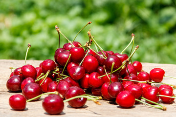 Fototapeta na wymiar Heap of fresh cherry on rustic wooden table outdoor