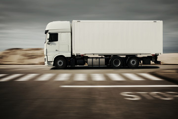 LKW fährt schnell auf einer Straße in der Wüste