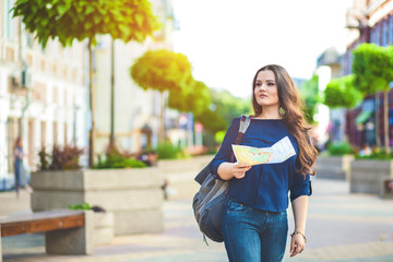 Girl tourist with map in hand on a city street travel guide, tourism in Europe