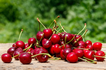 Obraz na płótnie Canvas Heap of fresh cherry on rustic wooden table outdoor