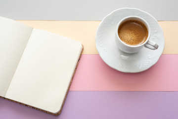 Taza de café vintage y una libreta con espacio para texto sobre un  fondo colorido de tonos pastel. 