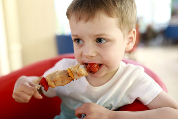 Kid eating chiken kebab