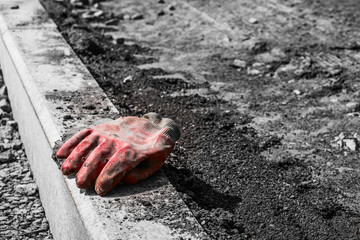 Red rubber glove is on the curb during the repair of the road