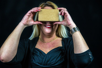 Blonde Frau nutzt Smartphone mit Pappkarton Datenbrille