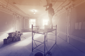 Workers  putty up ceiling walls in the room  in apartment is under construction, remodeling,...