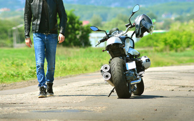 Obraz premium Cool guy in leather jacket and jeans walks to his motorcycle
