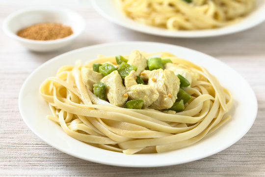 Chicken with green bell pepper and onion in mustard cream sauce on fettuccine pasta, photographed with natural light (Selective Focus, Focus in the middle of the image)