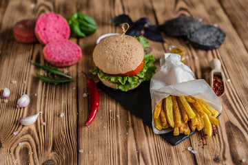 Tasty hamburger with meat and vegetables against a dark background. Fast food. It can be used as a background