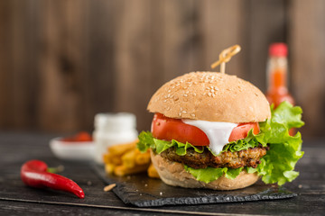 Tasty hamburger with meat and vegetables against a dark background. Fast food. It can be used as a background