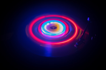 Turntable playing vinyl with glowing abstract lines concept on dark background