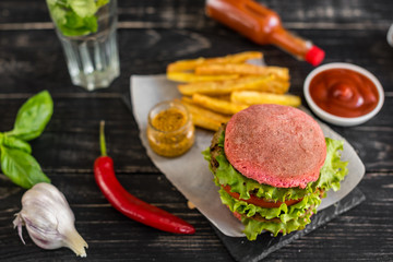Tasty hamburger with meat and vegetables against a dark background. Fast food. It can be used as a background