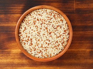 Raw Quinoa in wooden bowl, superfood. Brown wooden background, top view.